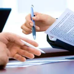 Dwie osoby analizują dokument, omawiając informację o warunkach zatrudnienia.