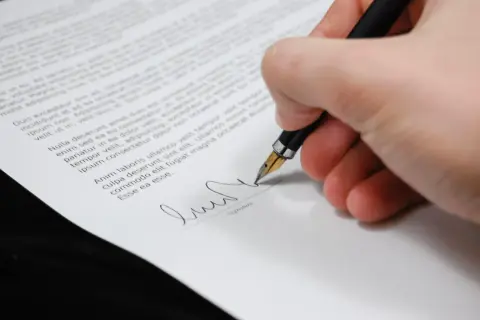 Podpisanie polskiej umowy w Niemczech. Dłoń z piórem podpisuje dokument.