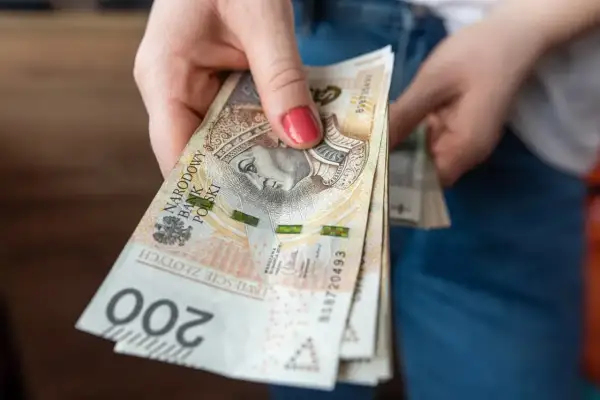 Dłoń trzyma plik banknotów 200 zł. Zastanawiasz się, ile za godzinę pracy?